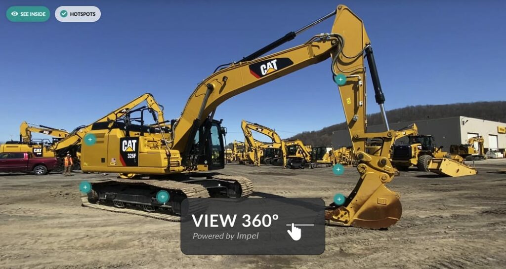Ein großer gelber Bagger von Caterpillar steht auf einer Baustelle. Er hat Kettenräder und einen langen Arm mit Schaufel. Auf dem Bild sind mehrere blaue Informationspunkte angebracht. Im Hintergrund sind weitere Baumaschinen und ein Gebäude zu sehen. Text im Vordergrund: VIEW 360° Powered by Impel.