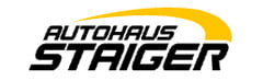 Logo mit dem Text Autohaus Staiger in schwarzer Schrift auf weißem Hintergrund. Über dem Text verläuft ein gelber Bogen.